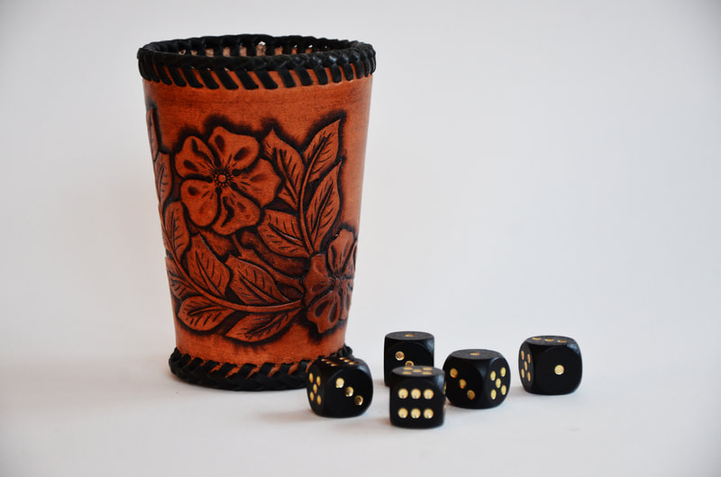 Würfelbecher aus Leder mit Blumen Punzierung und Flechtband umflochten.